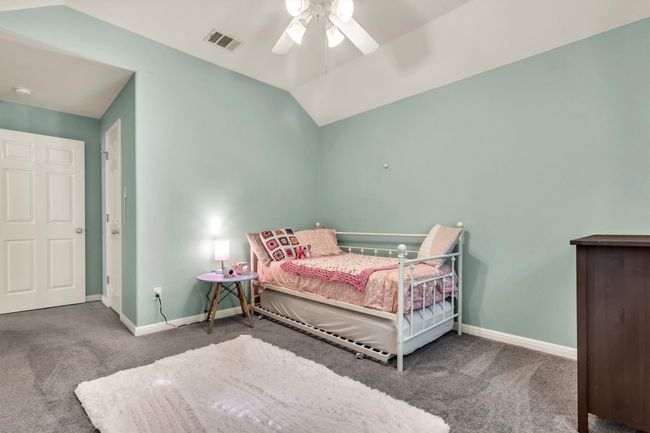 Carpeted bedroom featuring a ceiling fan, baseboards, lofted ceiling, and visible vents | Image 20