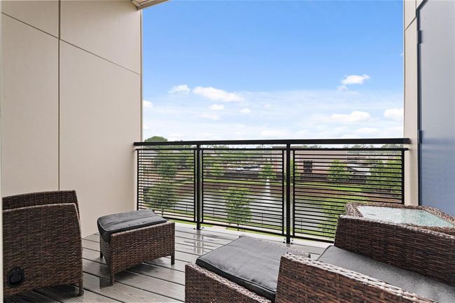 Outdoor balcony overlooking a serene view of trees and a water feature. Perfect for relaxation and enjoying the outdoors. | Image 11