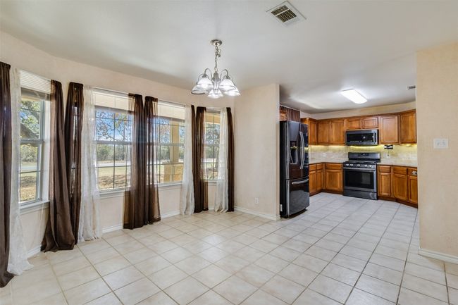 Kitchen featuring visible vents, black fridge, range with gas cooktop, stainless steel microwave, and a chandelier | Image 10