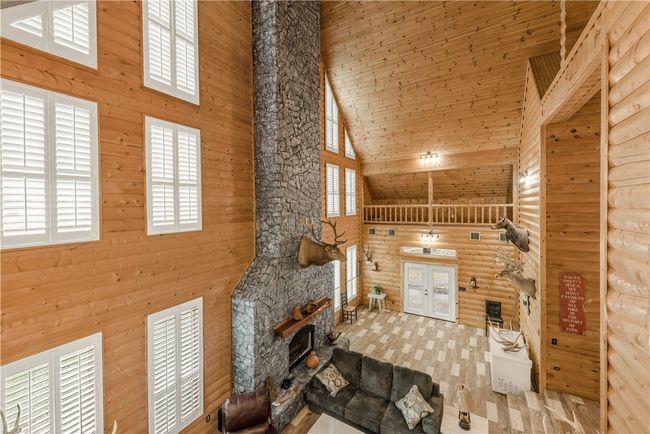 Living room featuring high vaulted ceiling, french doors, a fireplace, wooden walls, and wooden ceiling | Image 6