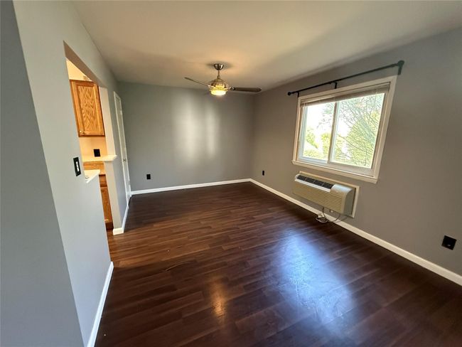 Spare room with dark wood finished floors, a ceiling fan, a wall unit AC, and baseboards | Image 5