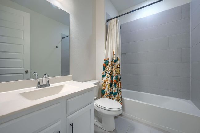 Bathroom with toilet, tile patterned floors, vanity, and shower / bathtub combination with curtain | Image 26