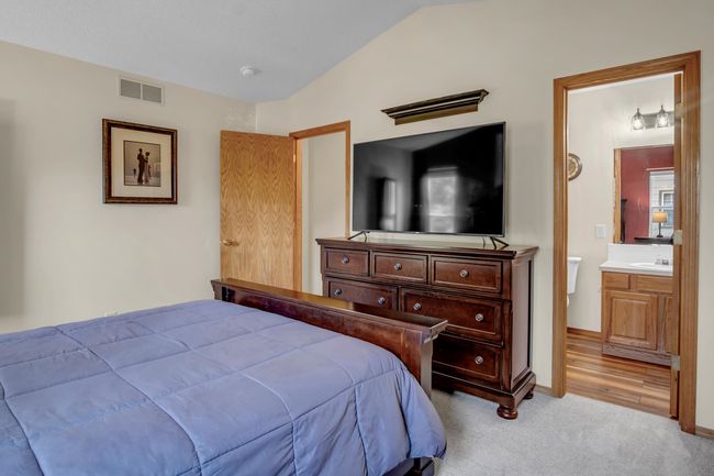 Bedroom featuring lofted ceiling, ensuite bath, light colored carpet, a sink, and baseboards | Image 19