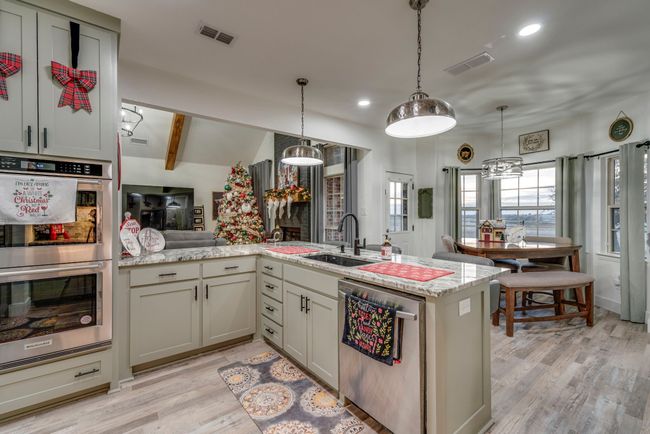 Kitchen featuring pendant lighting, light hardwood / wood-style floors, kitchen peninsula, and appliances with stainless steel finishes | Image 7