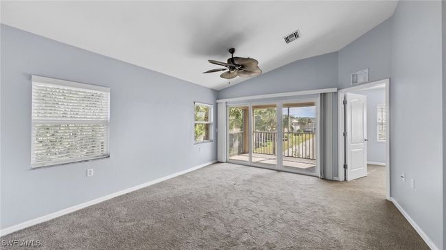 Carpeted empty room featuring visible vents, baseboards, vaulted ceiling, and ceiling fan | Image 6