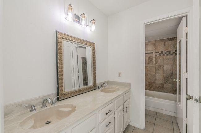 Bathroom with double vanity, tile patterned floors, and tub / shower combination | Image 18