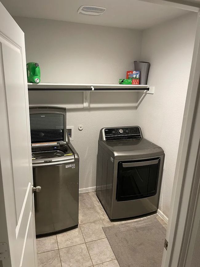 Washroom with laundry area, visible vents, light tile patterned floors, washing machine and clothes dryer, and baseboards | Image 11