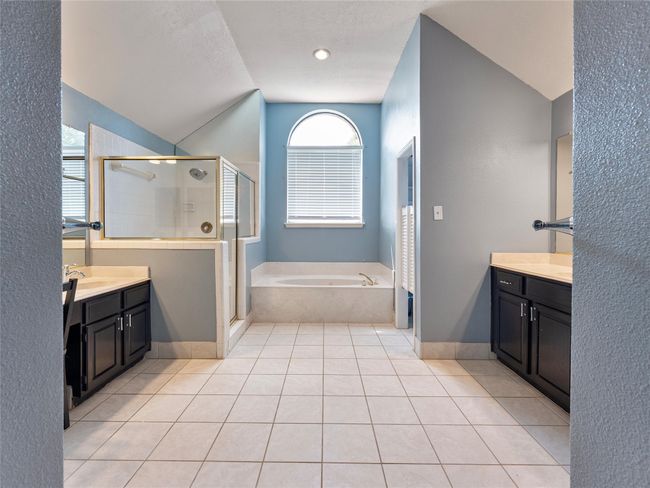 Full bathroom with vanity, a stall shower, a bath, tile patterned floors, and lofted ceiling | Image 16
