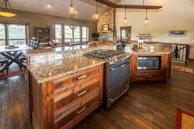Kitchen featuring stainless steel appliances, dark wood-style floors, vaulted ceiling, plenty of natural light, and open floor plan | Image 15