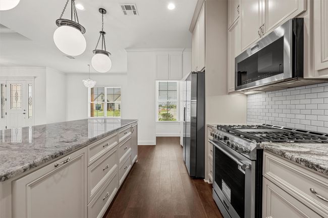 Kitchen with stainless steel appliances, backsplash, dark wood-style floors, light stone countertops, and recessed lighting | Image 8