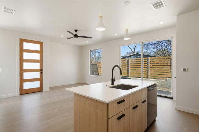 Kitchen with light brown cabinets, stainless steel dishwasher, a sink, and visible vents | Image 27