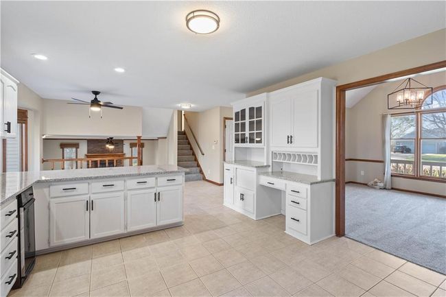 Kitchen featuring a peninsula, ceiling fan with notable chandelier, white cabinetry, light tile patterned floors, and baseboards | Image 23