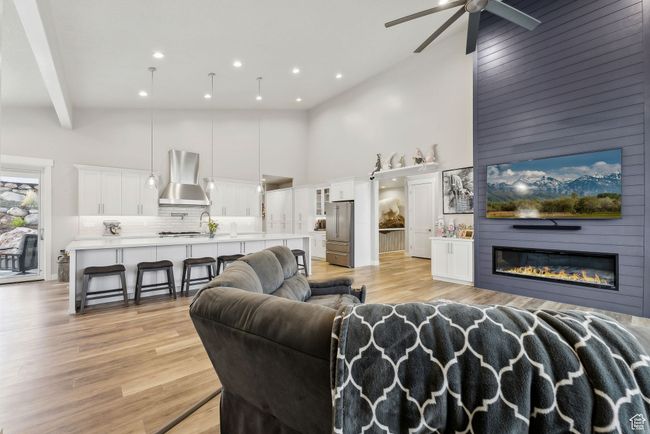 Living area with light wood-style floors, a ceiling fan, recessed lighting, and a high ceiling | Image 49