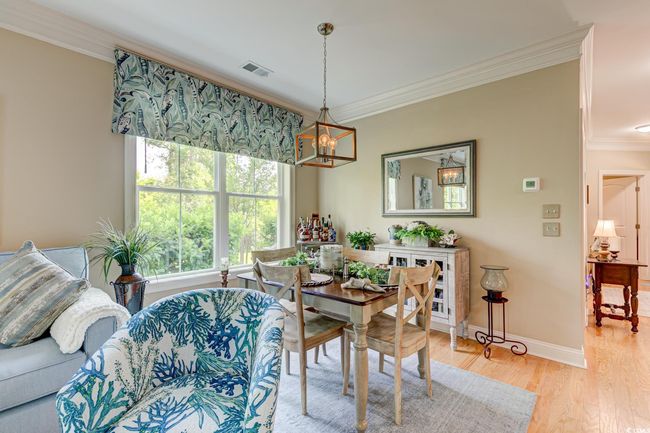 Dining area featuring a notable chandelier, light wood-type flooring, baseboards, ornamental molding, and visible vents | Image 10
