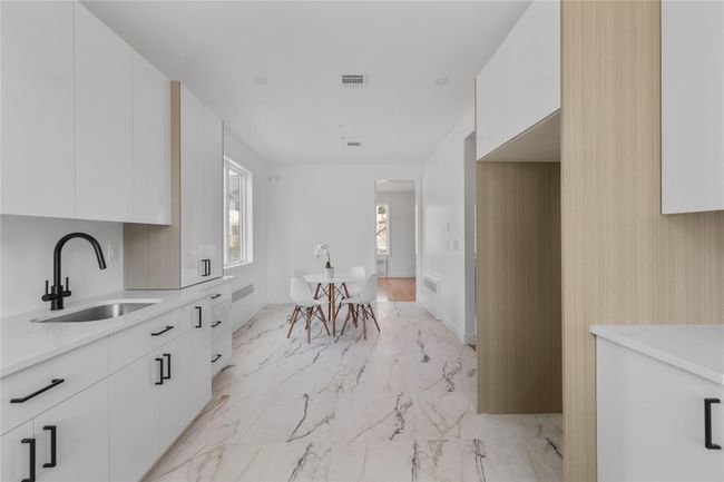 Kitchen with a sink, visible vents, white cabinetry, modern cabinets, and marble finish floor | Image 10