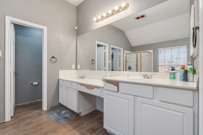 Bathroom featuring double vanity, a shower stall, wood finished floors, and vaulted ceiling | Image 28