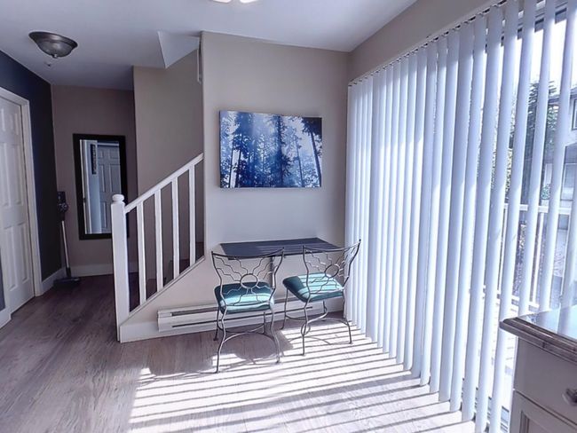 Interior space featuring a baseboard heating unit, baseboards, wood finished floors, and stairway | Image 9