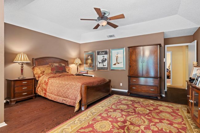 Bedroom featuring wood finished floors, a textured ceiling, ceiling fan, baseboards, and visible vents | Image 14