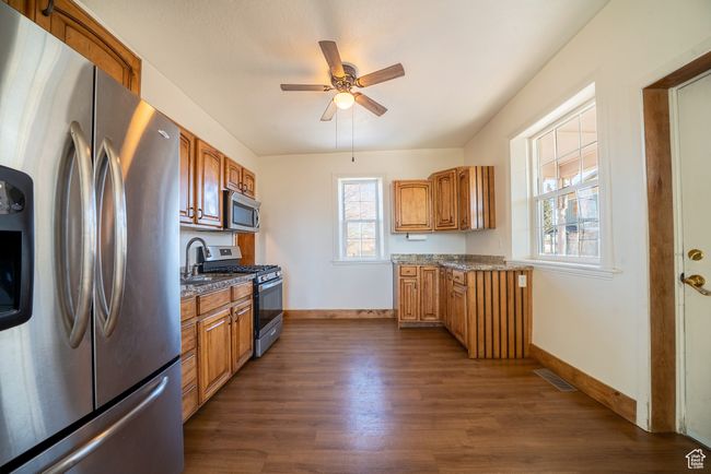 Kitchen with stainless steel appliances, dark wood-style flooring, visible vents, and baseboards | Image 23