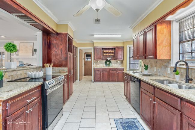 Kitchen featuring a sink, dishwashing machine, reddish brown cabinets, and stainless steel range with electric cooktop | Image 9