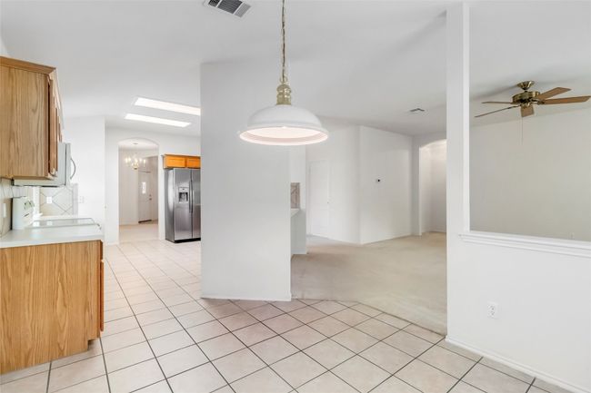 Kitchen featuring stainless steel fridge, stove, light tile patterned floors, ceiling fan, and light countertops | Image 18