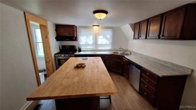 Kitchen with a wealth of natural light, appliances with stainless steel finishes, under cabinet range hood, a sink, and wood counters | Image 14