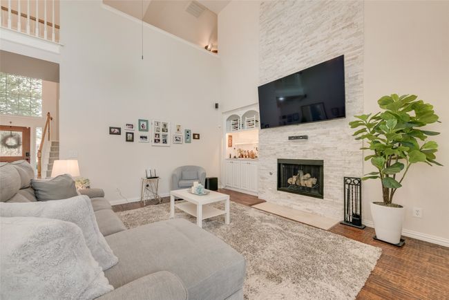 Living area featuring a towering ceiling, a stone fireplace, baseboards, and stairs | Image 10