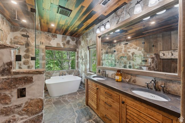 Bathroom featuring walk in shower, a soaking tub, double vanity, stone floors, and wooden ceiling | Image 19