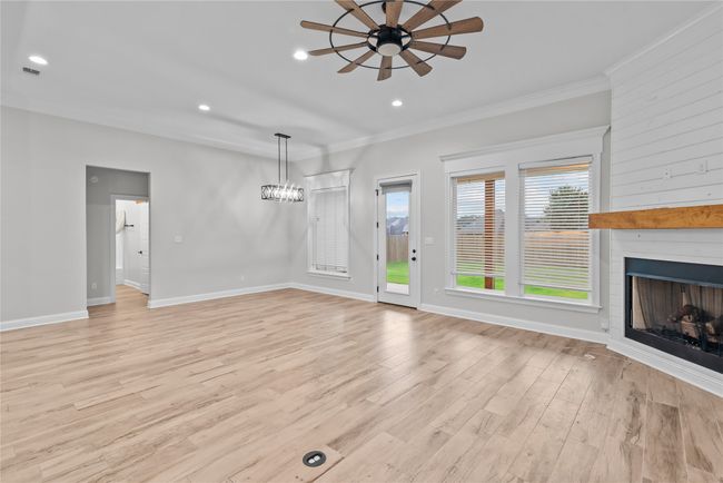 Unfurnished living room with light wood-style floors, recessed lighting, a ceiling fan, a fireplace, and ornamental molding | Image 4