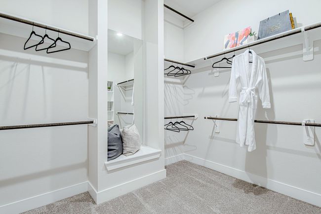 This expansive walk-in closet boasts custom shelving, double rods, and even a built-in bench with mirror—style and storage in one. | Image 28