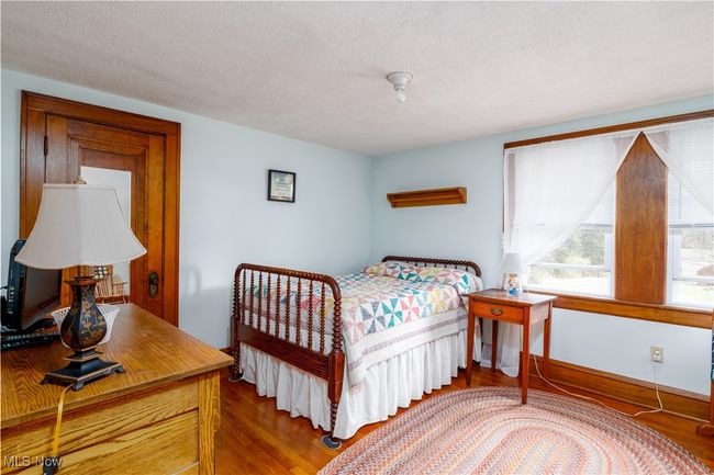 Bedroom with wood finished floors and a textured ceiling | Image 19