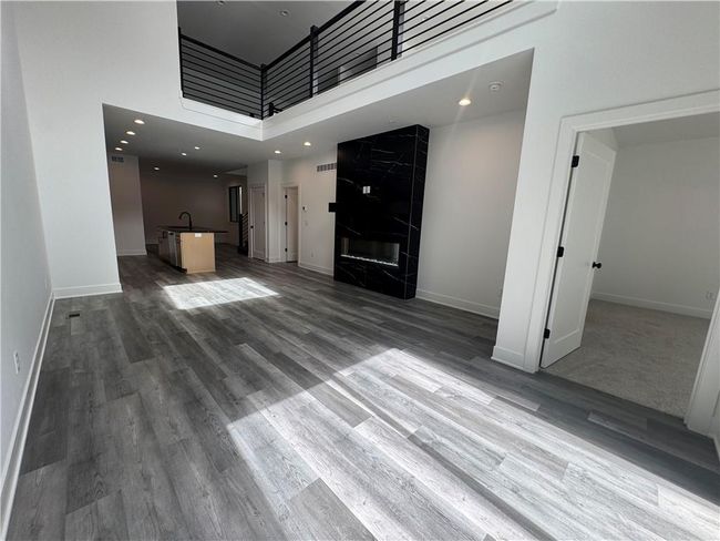 Unfurnished living room with baseboards, a high ceiling, wood finished floors, and a sink | Image 9