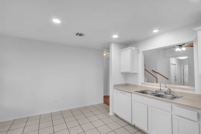 Kitchen with white dishwasher, light countertops, white cabinetry, recessed lighting, and ceiling fan | Image 11