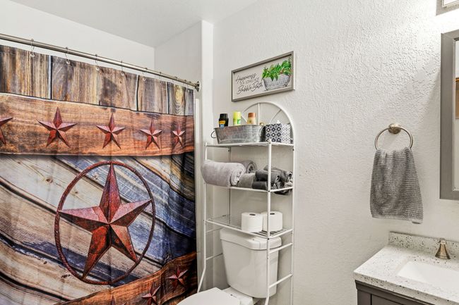 Separate apartment Full bath featuring toilet, vanity, a textured wall, and curtained shower | Image 74