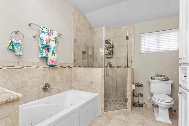 This is a spacious, well-lit bathroom featuring a large walk-in shower, a separate tub, and modern fixtures, with neutral tile throughout for a serene, clean look. | Image 30