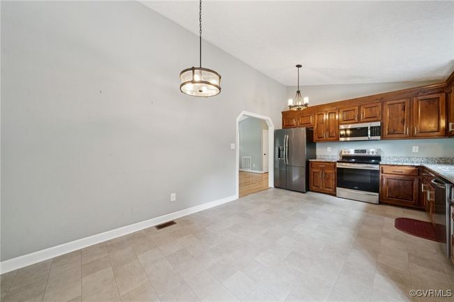 Kitchen featuring stainless steel appliances, baseboards, high vaulted ceiling, a chandelier, and arched walkways | Image 17