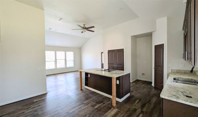 Kitchen featuring visible vents, open floor plan, a sink, an island with sink, and a kitchen bar | Image 12