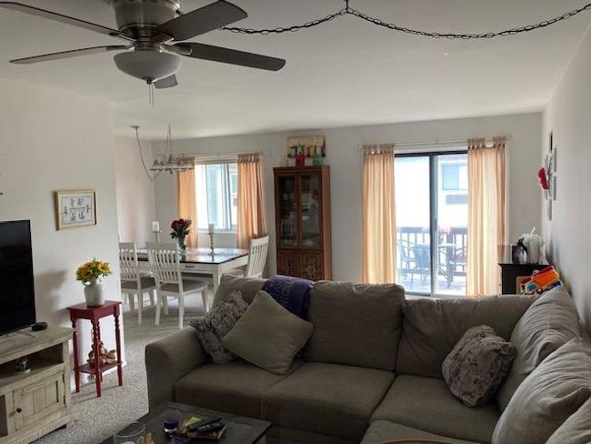 Carpeted living area with plenty of natural light, ceiling fan, and a chandelier | Image 10