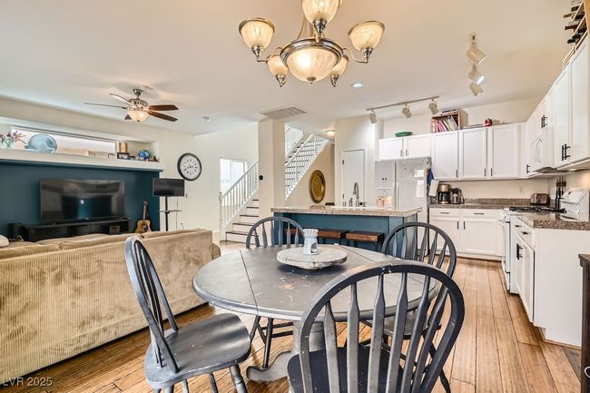 Dining space with visible vents, light wood-type flooring, stairway, and ceiling fan with notable chandelier | Image 10