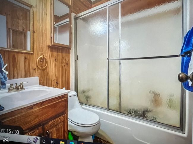 full bathroom featuring vanity, toilet, combined bath / shower with glass door, and wood walls | Image 47