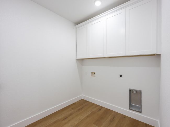 This bright laundry room offers upper cabinets for storage and all necessary utility hookups, making laundry day efficient and organized. | Image 28