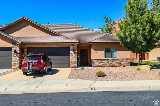 View of front of home featuring stone siding, an attached garage, driveway, and stucco siding | Image 7