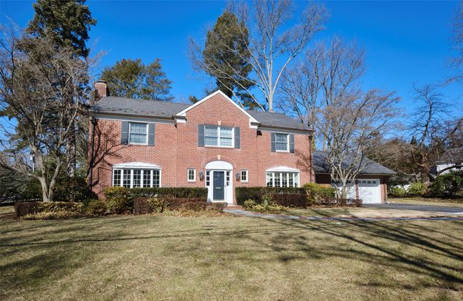 Colonial house with an attached garage, a front yard, a chimney, and brick siding | Image 16