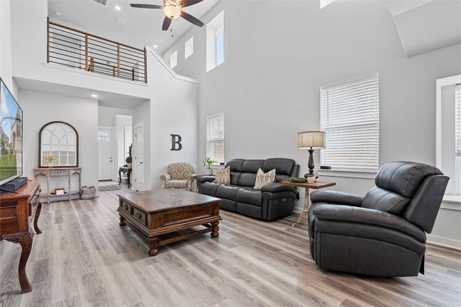 Living room with a ceiling fan, light wood-type flooring, recessed lighting, a towering ceiling, and baseboards | Image 8