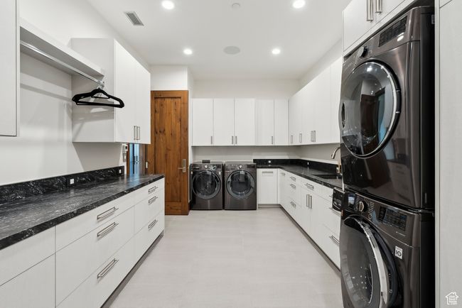 Laundry area featuring stacked washer and clothes dryer, a sink, recessed lighting, and light flooring | Image 37