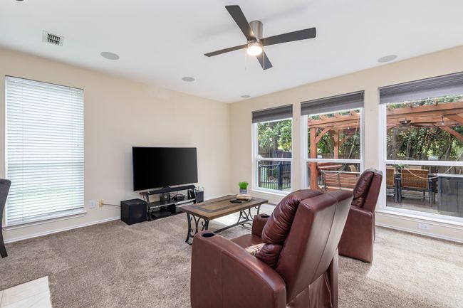 Living area featuring light colored carpet, a ceiling fan, and a tile fireplace | Image 11