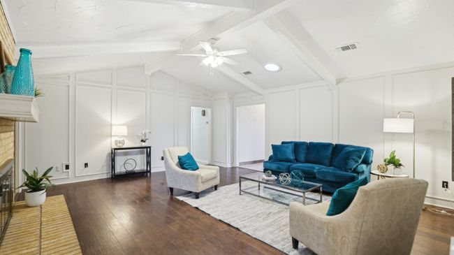 Living area featuring a decorative wall, vaulted ceiling with beams, a fireplace, and dark wood-style floors | Image 8