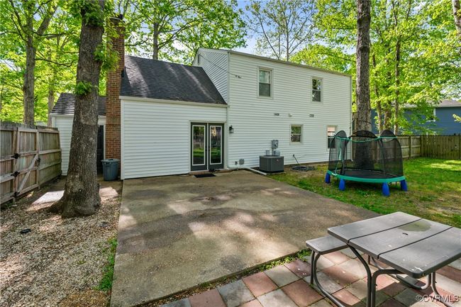 Rear view of house with a trampoline, a chimney, a patio area, a shingled roof, and a fenced backyard | Image 26