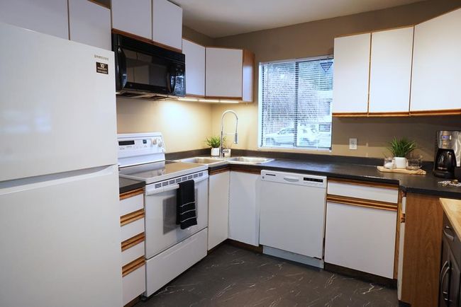 Kitchen featuring white appliances, white cabinetry, and dark countertops | Image 7
