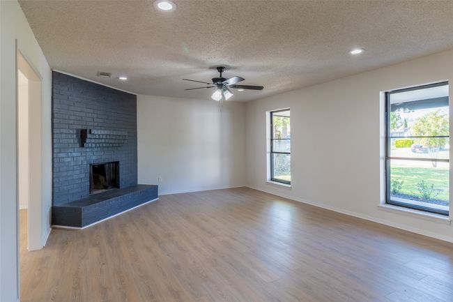 Unfurnished living room with wood finished floors, visible vents, a textured ceiling, and a healthy amount of sunlight | Image 23